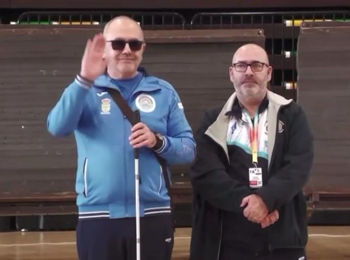 Antonio Manuel Hermida con chándal azul y bastón, acompañado en Langreo